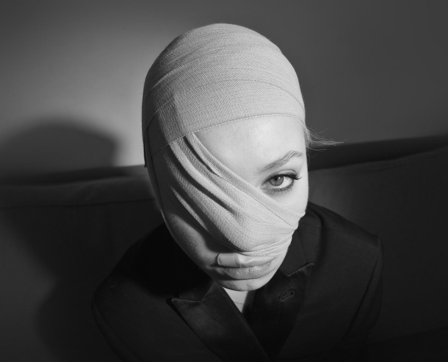 A performer with their head wrapped in bandages, looking towards the camera
